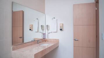 Ein Badezimmer mit Waschbecken, Spiegel und zwei Seifenspendern.