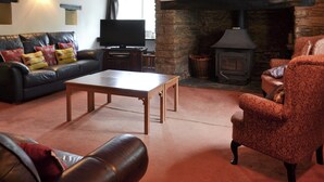 Una sala de estar acogedora con chimenea, sofá de cuero y televisión.