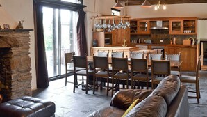 Una cocina rústica con armarios de madera, chimenea de piedra y un comedor con sofá y sillones de cuero.