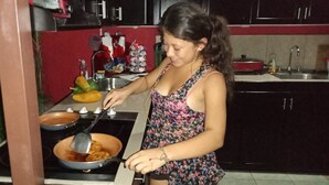 Una persona cocina en una cocina equipada con estufa, ollas y diferentes utensilios.
