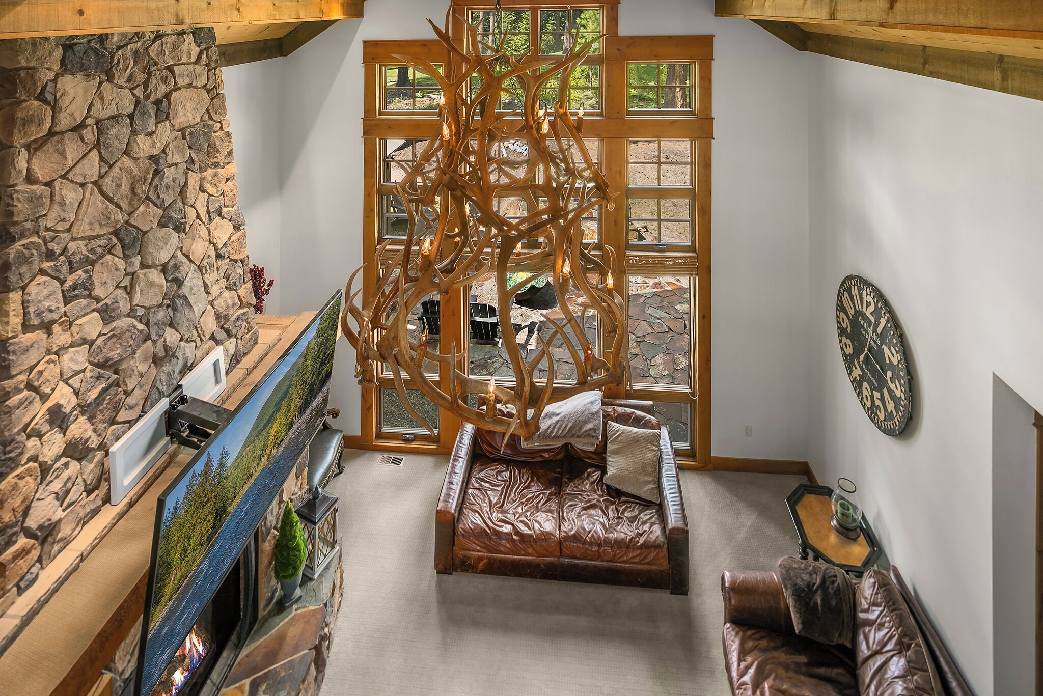 Ein gemütlicher Raum mit Steinwand, Kamin, großem Fenster, Holzboden und Ledersofa.