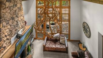 Ein gemütlicher Raum mit Steinwand, Kamin, großem Fenster, Holzboden und Ledersofa.