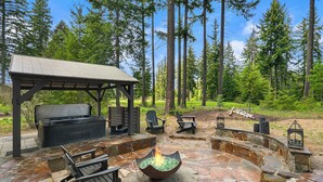 An outdoor patio with stone flooring, a fire pit, seating, and a covered area with a grill. - Evergreen Escape Estates with lots of amenities ! AVAILABLE FOR LONG TERM  (Cle Elum)
