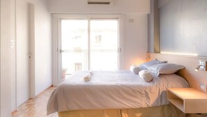 Ein Schlafzimmer mit Bett, Nachttisch, Fenster und Tür.
