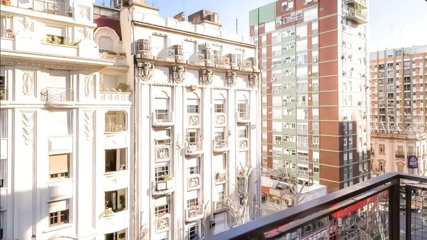 Ein mehrgeschossiges Gebäude mit aufwendigen architektonischen Details, darunter dekorative Stuckarbeiten und ein Balkon mit Geländern.