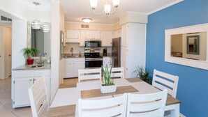 A modern kitchen with white cabinets, a dining table with chairs, and a chandelier. - 143 By the Sea * Gated Myrtle Beach Resort * 2/2 (Horry County)
