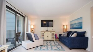 A living room with a sofa, a chair, a TV, and a painting. - 143 By the Sea * Gated Myrtle Beach Resort * 2/2 (Horry County)