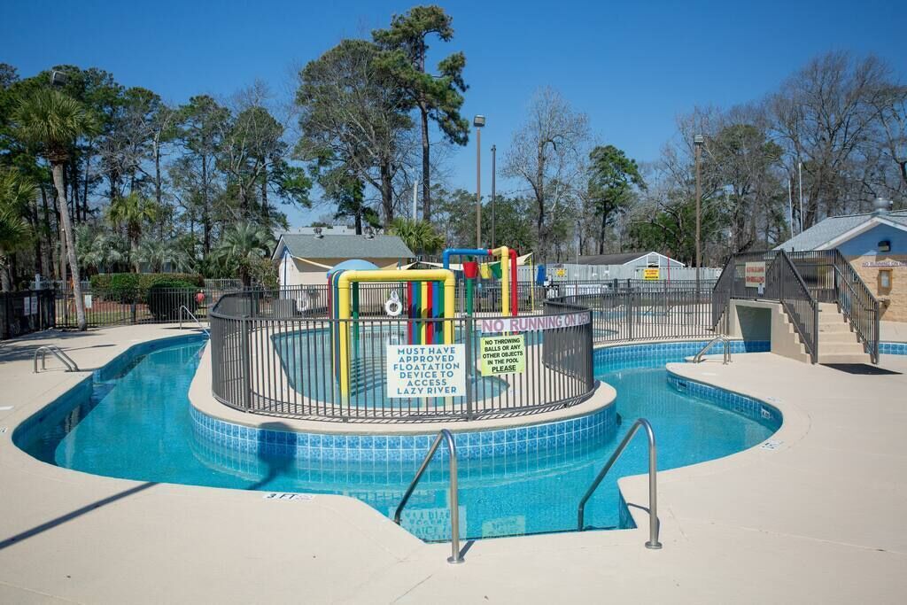 A swimming pool with a safety fence, a lifeguard tower, and a sign indicating no running on the deck.