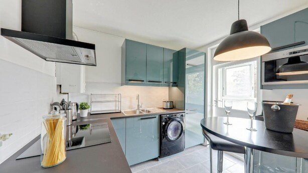 A modern kitchen with a built-in washing machine, a dining area with a round table, and a large window providing natural light. - Apartment coup de coeur, 3 bedrooms, 10 minutes from Rouen, Netflix (Mont-Saint-Aignan)