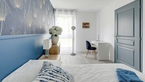 A bedroom with a bed, a desk, a chair, a vase with flowers, and a picture on the wall. - Apartment coup de coeur, 3 bedrooms, 10 minutes from Rouen, Netflix (Mont-Saint-Aignan)