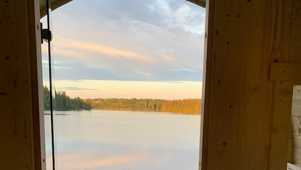 An open wooden door leading to a view of a calm lake with a grassy area in front. - Lövanäs Newly built modern house in a secluded location directly on the lake with its own jetty, boat (Korsberga)