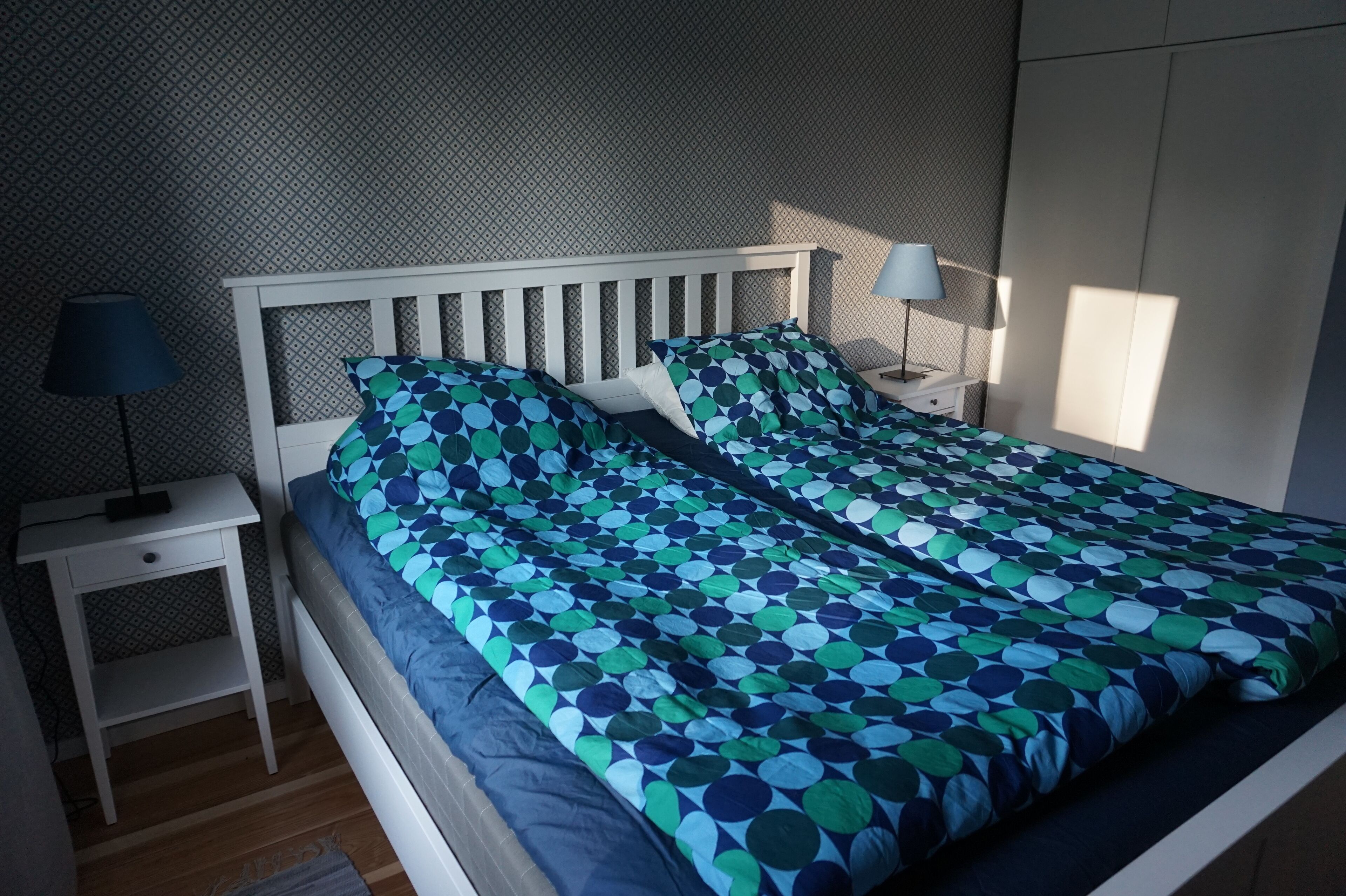 Una camera da letto con un letto, due comodini, una lampada e un armadio.