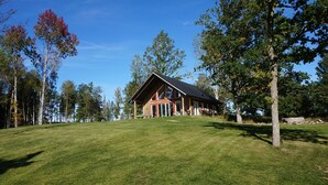 A lodge with a large front porch, surrounded by a grassy lawn and tall trees. - Lövanäs Newly built modern house in a secluded location directly on the lake with its own jetty, boat (Korsberga)