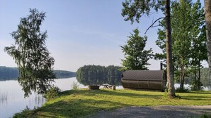 A lakeside cabin with a gravel path leading to it, surrounded by trees and a calm lake. - Lövanäs Newly built modern house in a secluded location directly on the lake with its own jetty, boat (Korsberga)