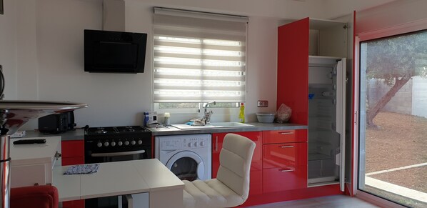 Une cuisine de taille réduite équipée d’une cuisinière, d’un lave-linge et d’un évier.