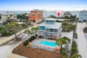 A beachfront property with a swimming pool, a deck, and a view of the ocean.