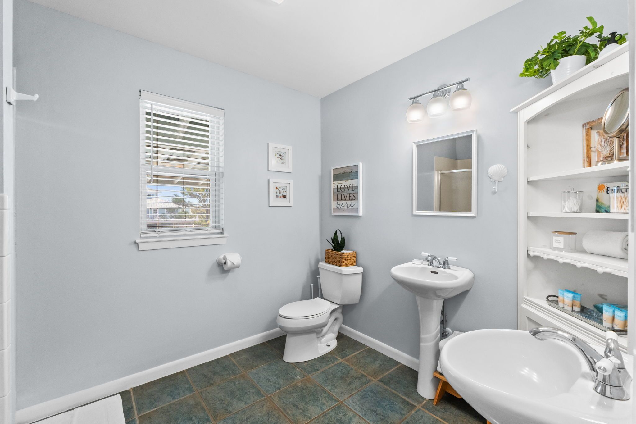 A bathroom with a toilet, sink, and window with blinds.