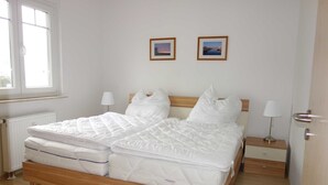 En dobbeltseng med træramme, to sengeborde med lamper, og to billeder hængende på væggen.