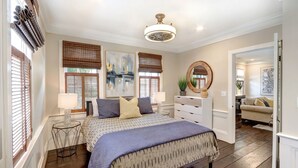 A bedroom with a bed, bedside lamps, a dresser, and a mirror. - 1828 Cottage | Heated Pool in Private Garden | Sleeps 6 | Pets | On-Site Parking (Savannah)