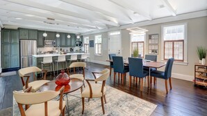 A spacious kitchen with modern appliances, a dining area with a large table and chairs, and a view of the adjacent living room. - 1828 Cottage | Heated Pool in Private Garden | Sleeps 6 | Pets | On-Site Parking (Savannah)