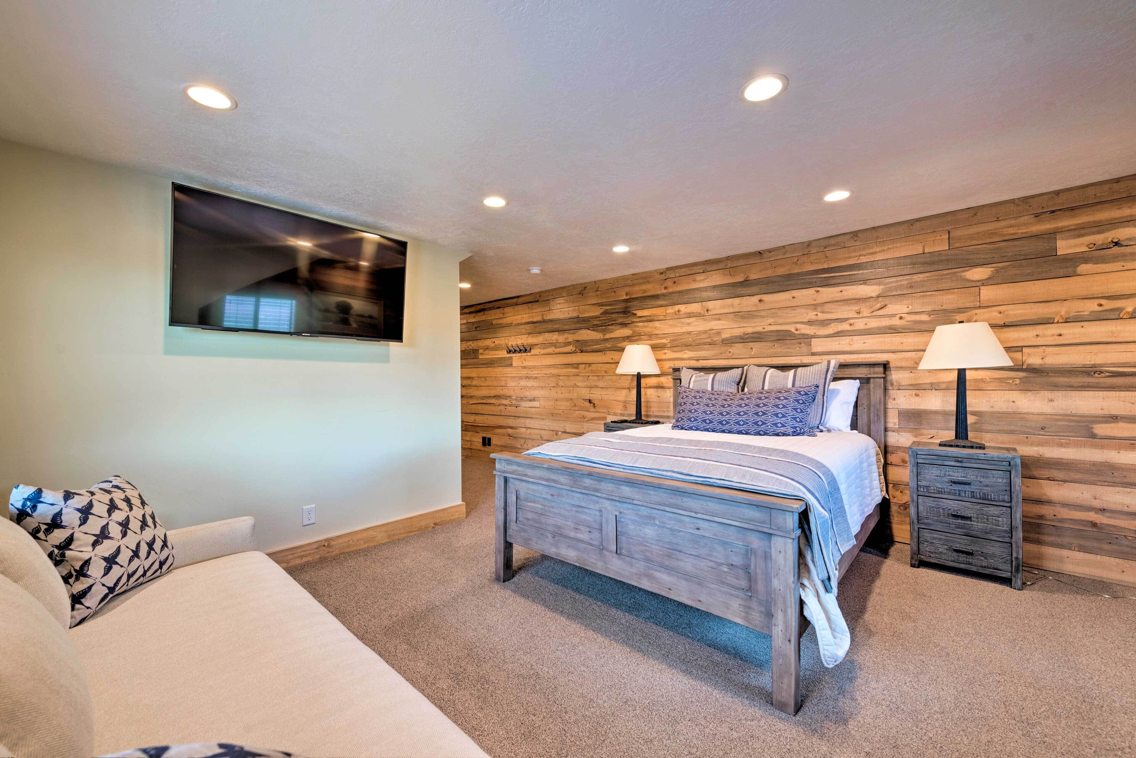 Un dormitorio con pared de madera, una cama con dos mesitas de noche y una ventana.