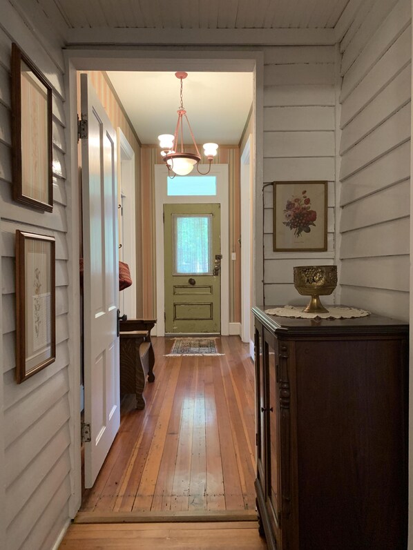 A hallway with wooden floors, a green door, and a chandelier.