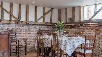 Un coin repas avec un mur en briques, des poutres en bois et une table dressée pour six personnes.