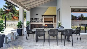 Un patio exterior con una parrilla empotrada, zona de estar y plantas en macetas.