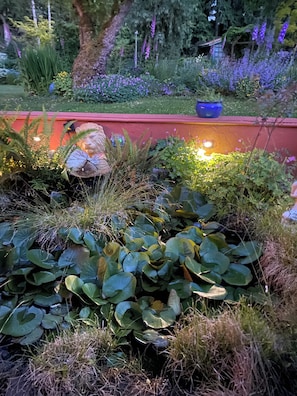 Stroll through the serene garden, surrounded by lush plants and vibrant flowers, with a beautiful backdrop of a red wall.