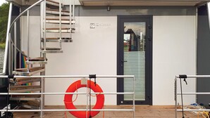 A lifeboat with a metal staircase, a door labeled "ESCAPADE," and a red life ring. - Cozy ship in Nieuwpoort with WiFi (Nieuwpoort)