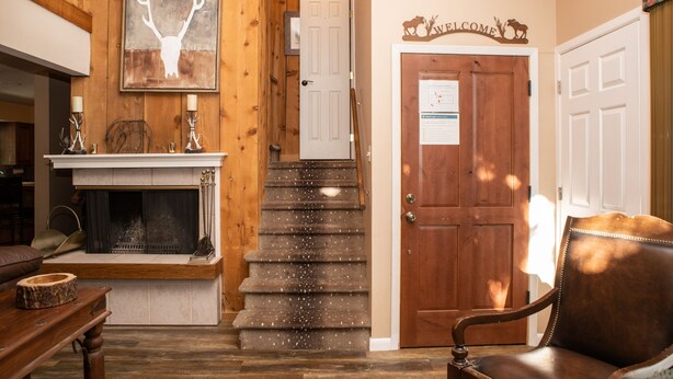 Un interior de madera con chimenea, una escalera y un sillón de cuero.