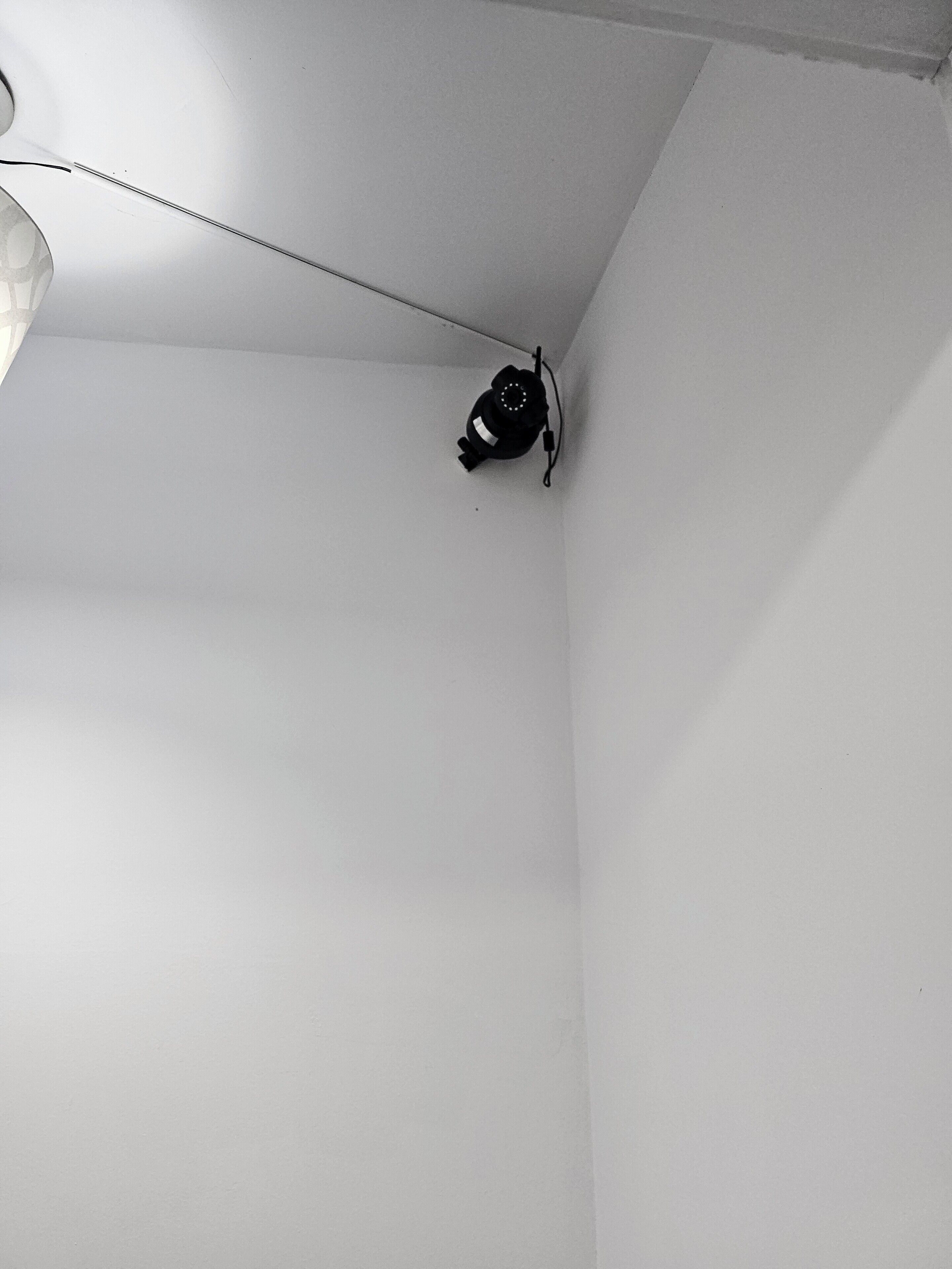 A corner of a room with white walls and a ceiling light fixture.