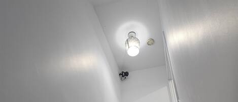 A staircase with white walls and a light fixture at the top.