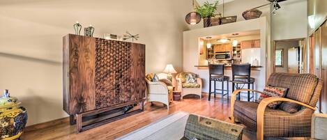 A spacious living room with a large wooden cabinet, a comfortable sofa, and a dining area with a kitchen in the background.