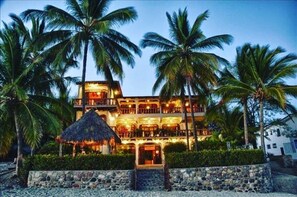Hotel features a spacious balcony area surrounded by lush palm trees and a central courtyard.