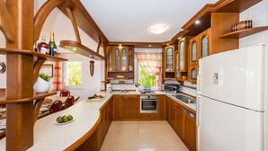 Une cuisine avec des meubles de rangement en bois, un réfrigérateur blanc, un four à micro-ondes et un évier.