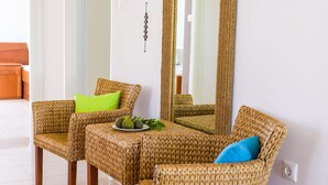 Une pièce meublée avec des meubles en osier, notamment un canapé et un fauteuil, séparés par une petite table.