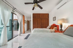 Ein Hotelzimmer mit zwei Betten, einem Deckenventilator, einer Klimaanlage, einem Holzschrank und Blick ins Freie.