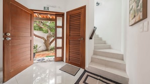 Une entrée propre et moderne, avec une porte en bois, un escalier et une vue sur un jardin.