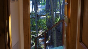 A wooden staircase leading to a balcony with a view of trees and a road. - Familia Piatti Suites (Ushuaia)