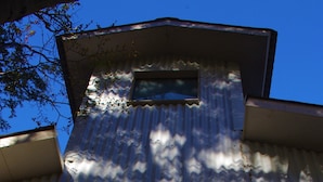 A building with a corrugated metal exterior, a wooden door, and a small window. - Familia Piatti Suites (Ushuaia)
