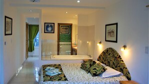 A bedroom with a bed, a bathroom with a bathtub, and a hallway leading to a balcony. - Familia Piatti Suites (Ushuaia)