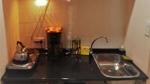 A compact kitchen with a stove, kettle, sink, and cabinets. - Familia Piatti Suites (Ushuaia)
