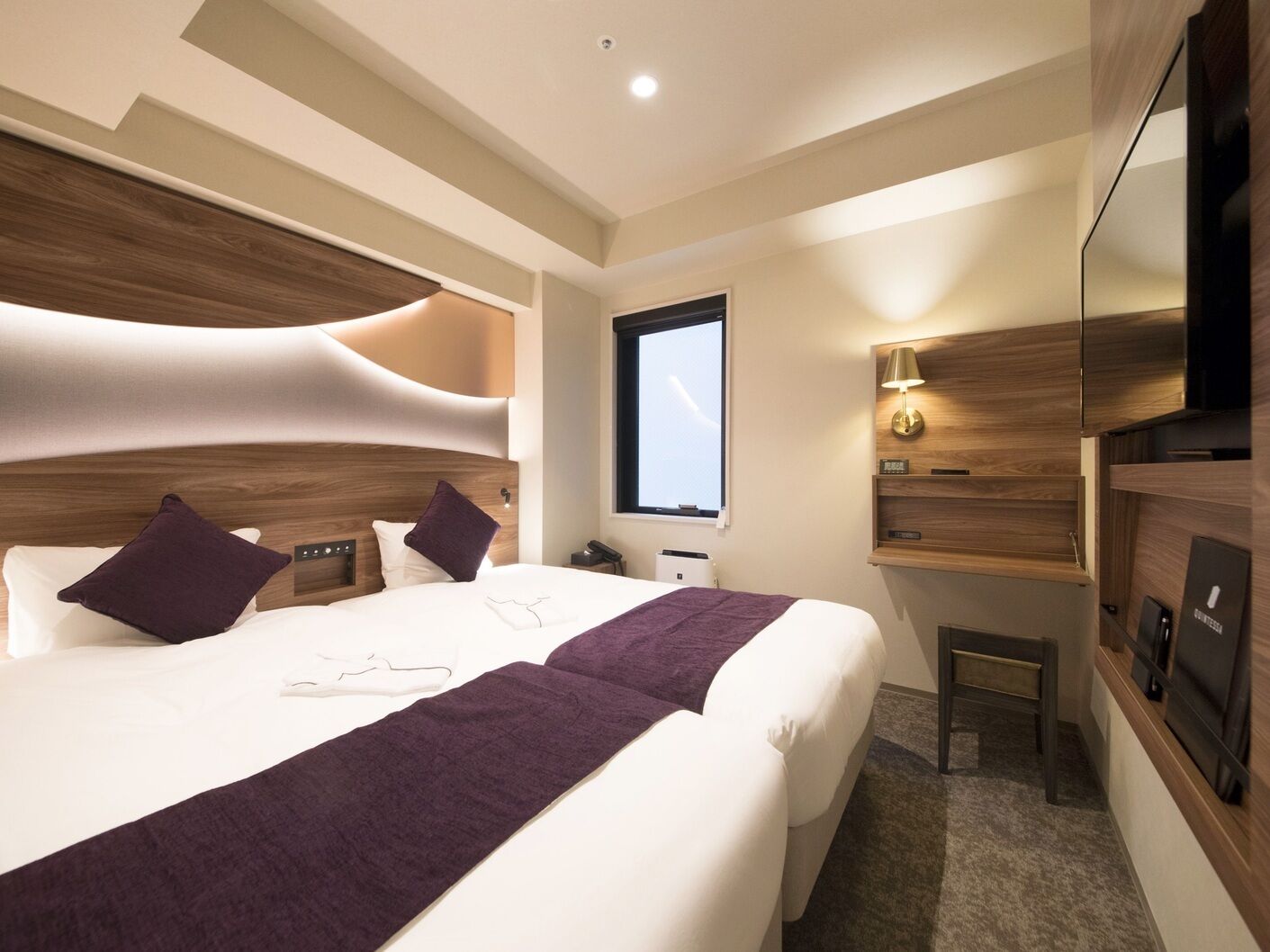 Une chambre d’hôtel moderne avec un grand lit, une table de chevet, une télévision et une fenêtre.