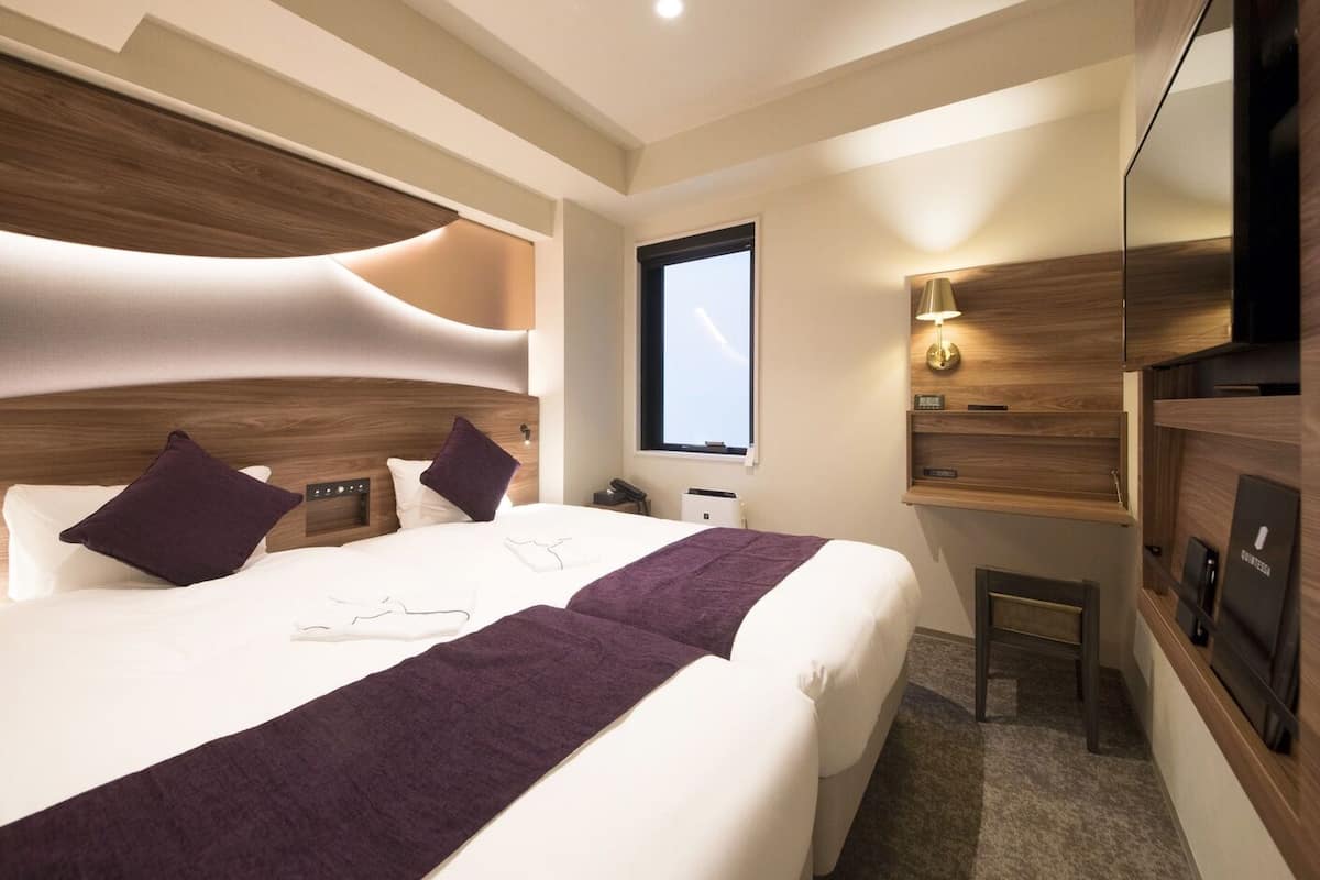Une chambre d’hôtel moderne avec un grand lit, une table de chevet, une télévision et une fenêtre.
