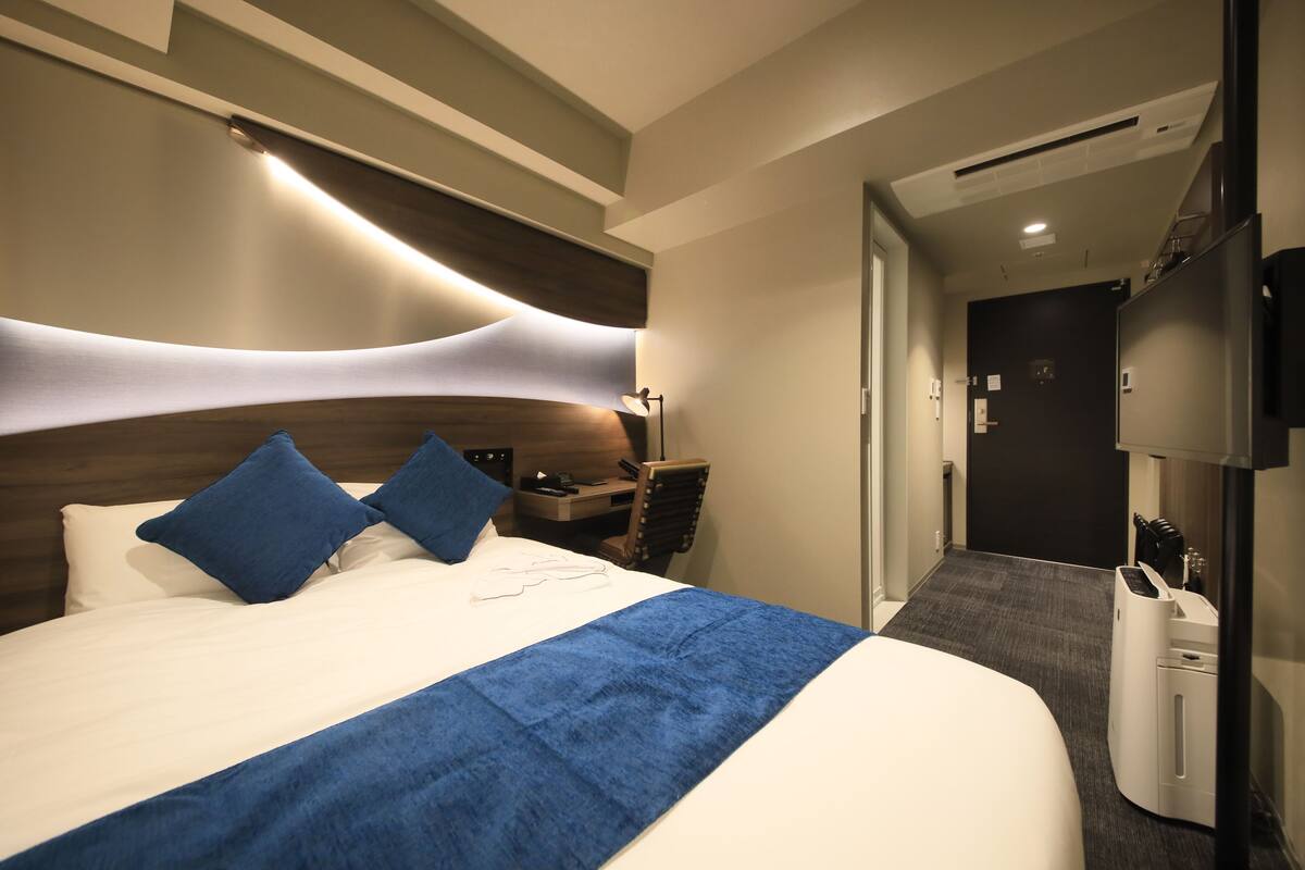 Une chambre d’hôtel moderne avec un grand lit, un bureau et une télévision.