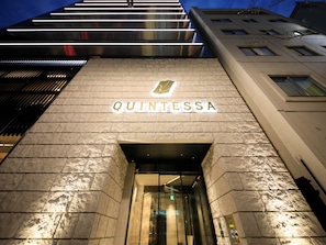 The exterior of the Quintessa hotel with a prominent illuminated sign and a modern entrance.