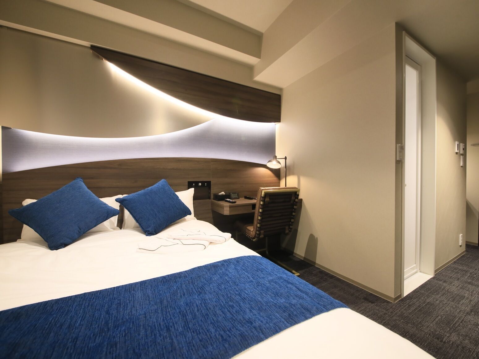 Une chambre d’hôtel avec un grand lit, un bureau et une chaise.