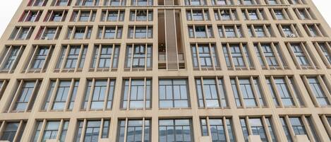 A tall, modern building with a grid of windows and a central entrance.