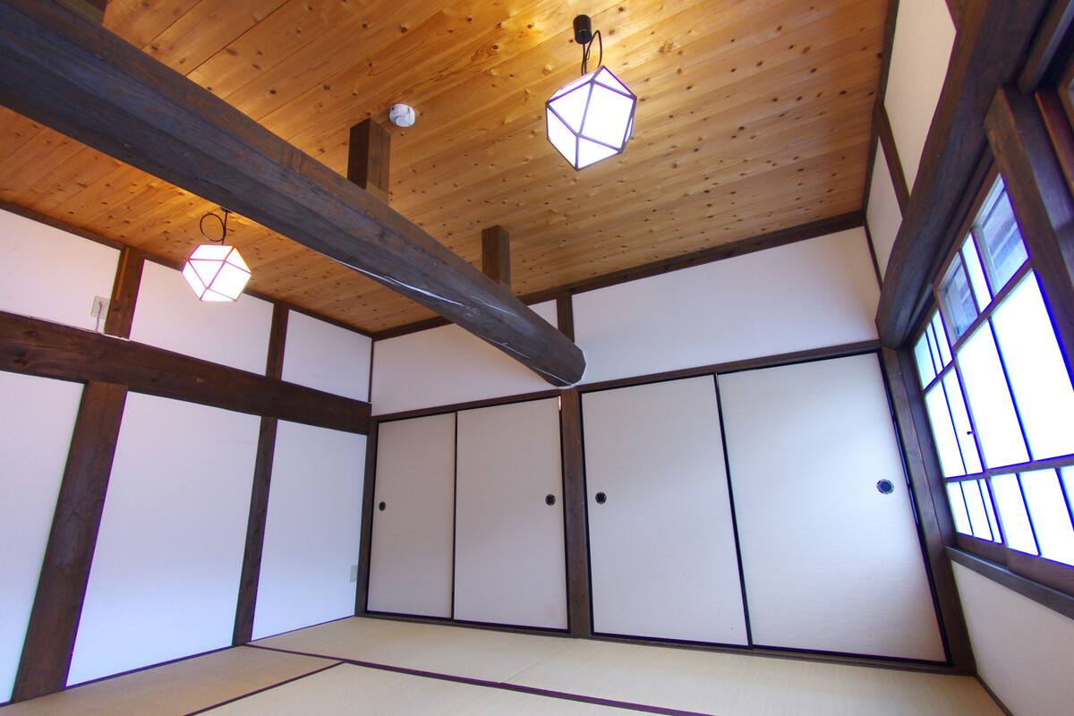 A traditional Japanese room with tatami flooring, shoji screens, and wooden beams.